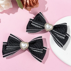 Détail de barrettes à nœud en ruban noir avec perles en cœur et bords rayés argent
