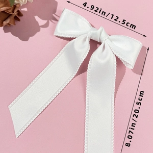 Détails de taille d'un nœud papillon en satin blanc avec de longs rubans et bords festonnés