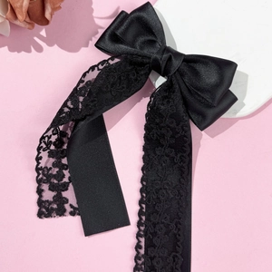 Dettaglio di un elegante fermaglio per capelli in raso nero con nastri in pizzo