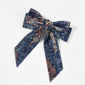 Close-up of blue denim bow hair clip with rose gold sequins on a white background