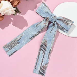 Detail of light blue denim hair clip featuring shimmering sequins and long ribbon streamers