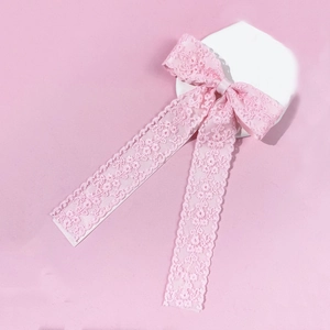 Detail of soft pink floral lace bow hairclip with elegant long ribbons on stone stand