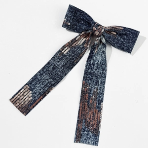 Detailed view of dark blue denim bow hair clip with rose gold sequins and long ribbons