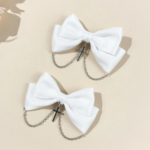 Détail de barrettes à nœuds en satin blanc avec chaînes à croix argentées au style gothique