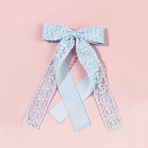 Detail shot of light blue lace and satin bow hair clip with elegant long ribbons
