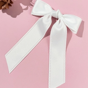 Gros plan sur un nœud en satin blanc avec bordure ondulée et longs rubans élégants