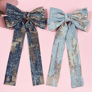Denim bow hair clip with gold sequins and long ribbon tassels on pink background