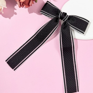 Detail view of a black lace bow hair clip with pink stripes and scalloped edges