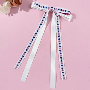 Detail of white bow hair clip with embroidered blue hearts and pink floral streamers