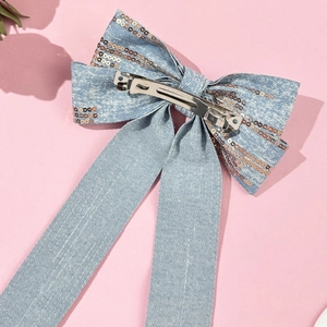 Close-up of denim bow hair clip with rose gold sequins and silver metal spring fastener