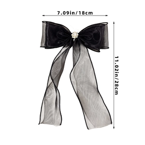 Macro shot of black mesh bow hairclip with central pearl and rhinestone embellishments