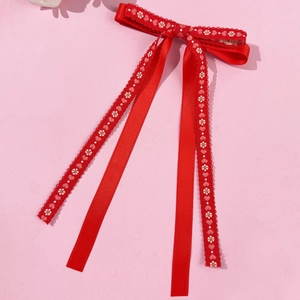 Detail of red ribbon hair clip with delicate white floral and heart embroidery pattern