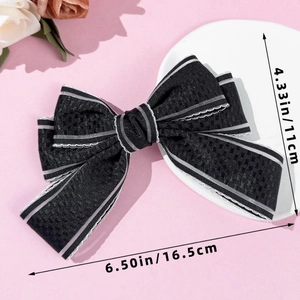 Detail view of black bow hair clip with silver-grey stripes and textured fabric finish