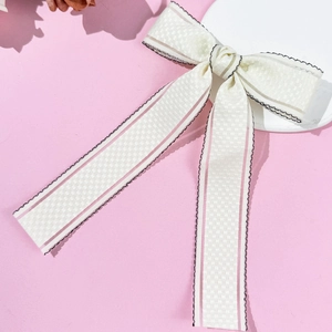 Lace-trimmed bow hair clip with pink stripes and long streamers on a styling stand