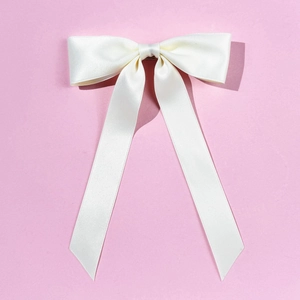 Dettaglio del fiocco per capelli in raso bianco con nastri lunghi su fondo rosa