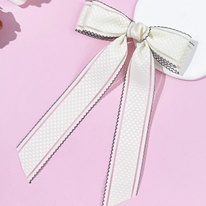 Détail d'un nœud papillon crème à rayures roses et bordures ondulées noires cousues