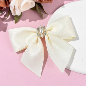 Détail macro du nœud en satin crème avec grappe florale de perles et de strass brillants