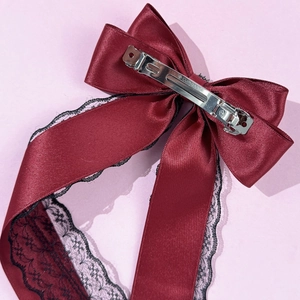Detailed view of burgundy satin bow hair clip with black lace and silver spring metal fastener
