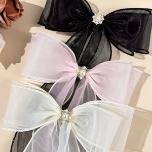 Detail of elegant mesh bow hair clips with central pearl and rhinestone embellishments