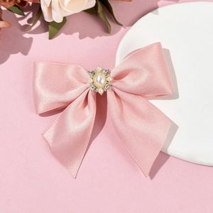 Gros plan sur le nœud papillon en satin rose avec perle centrale et décor en strass