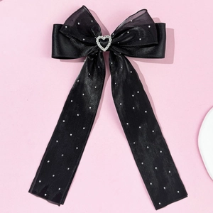 Détail d'un nœud papillon noir avec cristal en cœur et rubans longs ornés de strass