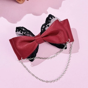 Détail d'un nœud en satin bordeaux avec dentelle noire et chaînes métalliques suspendues