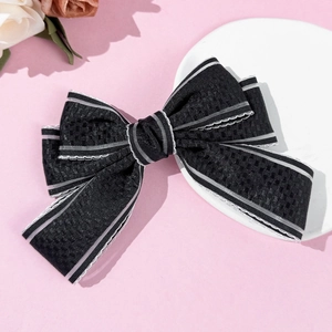 Detail view of black lace bow hair clip with textured fabric and white edge stitching