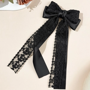 Detailed close-up of a black lace satin bow hair clip with elegant long flowing ribbons