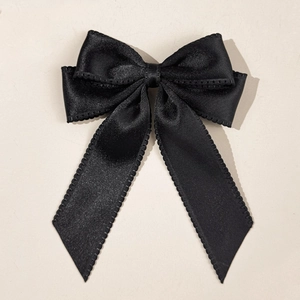 Top view of a black double-layered satin bow hair clip with decorative scalloped edges