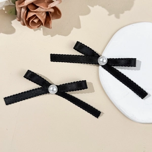 Détail de pinces à cheveux noeud en satin noir avec perles et bords en dentelle