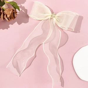 Detail view of cream organza bow hair clip with rhinestone and pearl floral center