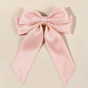 Close-up of pink satin bow hair clip with double-layered scalloped lace edges