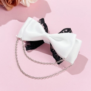 Détail d'une barrette nœud en satin blanc avec dentelle noire et chaînes argentées