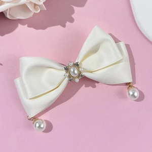 Detail of white satin bow hairclip with oval faux pearl and rhinestone centerpiece