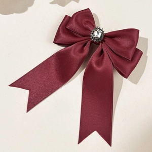 Detailed view of dark red satin bow hair clip with luxury rhinestone centerpiece