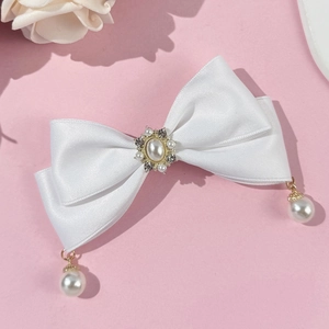 Detail of white satin bow hair clip with vintage pearl and rhinestone center decoration