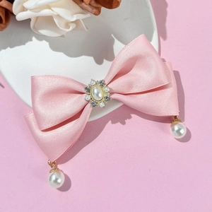 Detailed macro view of pink satin bow hairclip with vintage pearls and sparkling rhinestones