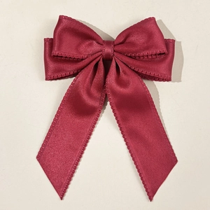 Detailed macro view of burgundy satin bow hair clip with elegant wavy scalloped edges