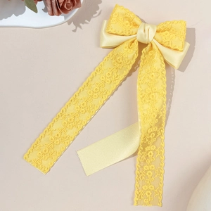 Detailed close-up of yellow lace ribbon hair clip featuring elegant floral textures
