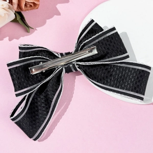 Elegant French style striped bow hair clip with silver edges on a pink display stand