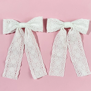 Detail of white lace bow hair clips with hollow floral patterns and long tassels