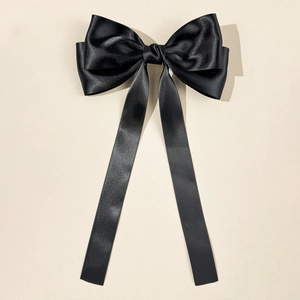 Détail du nœud papillon en satin noir avec de longs rubans fluides élégants