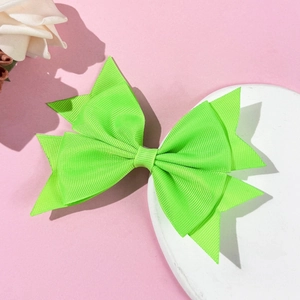 Dettaglio di un fiocco per capelli in grosgrain verde fluo su un espositore in pietra