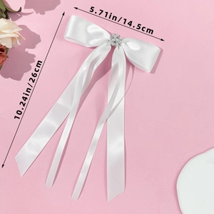 Detailed view of white satin ribbon bow with pearls and rhinestones showing size 26x14.5cm