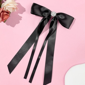Detail view of black satin bow hair clip with pearl flower center and long ribbons