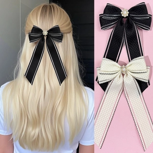 Détail de barrettes à nœuds à carreaux avec perles et strass en noir et blanc cassé