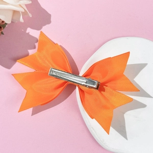 Fermaglio per capelli con fiocco in nastro grosgrain arancione su sfondo rosa con rose
