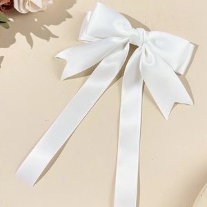 Dettaglio macro del fermaglio per capelli in raso bianco con fiocco e nastri eleganti
