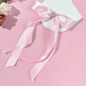 Detail of pink satin bow hair clip with cluster pearl center and long flowing ribbons