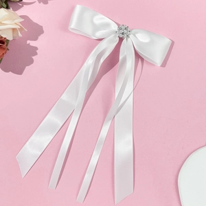 Close-up of white satin bow hair clip with faux pearl and rhinestone center detailing